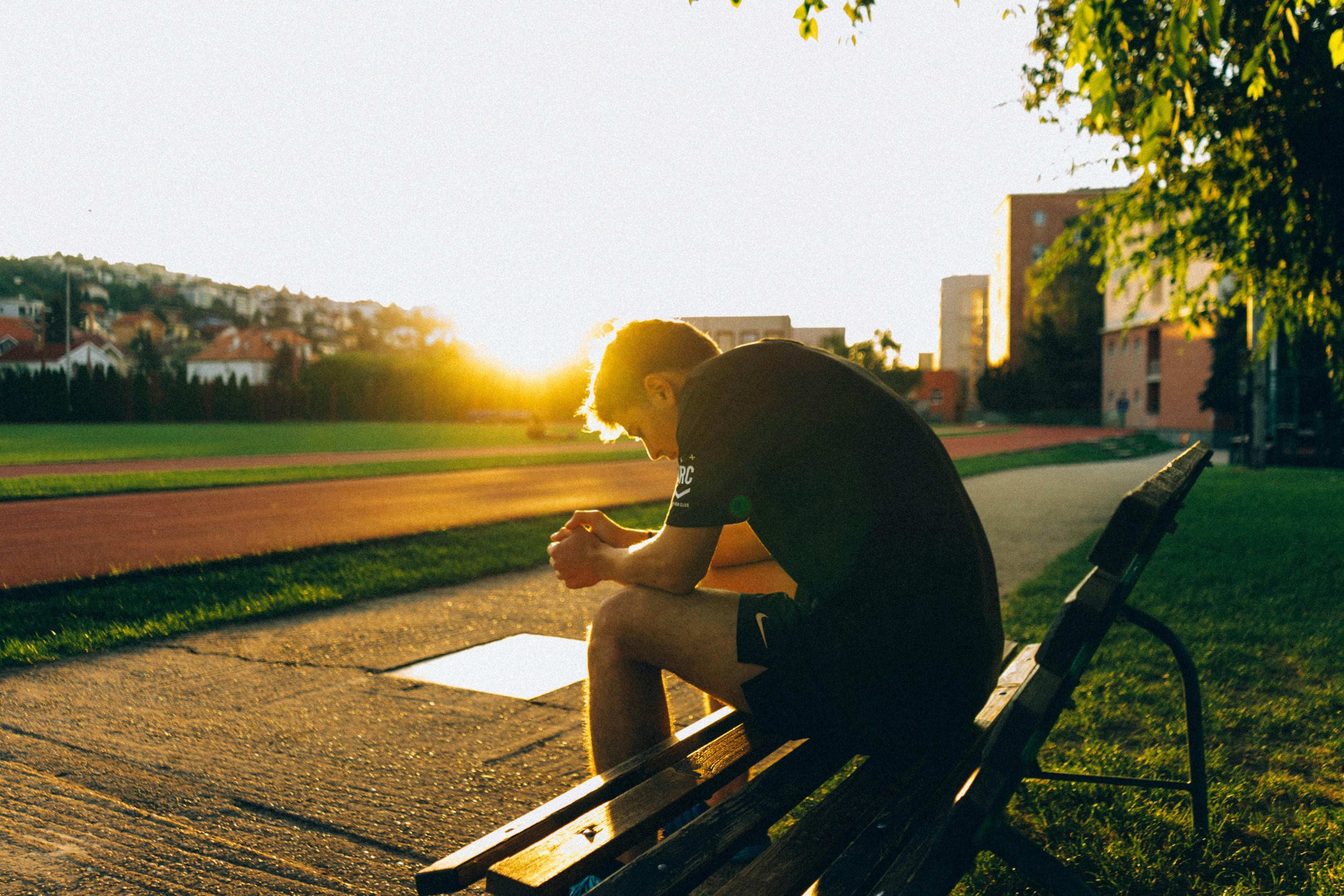 Photo by Martin  Péchy: https://www.pexels.com/photo/man-sitting-on-bench-near-track-field-while-sun-is-setting-1436145/