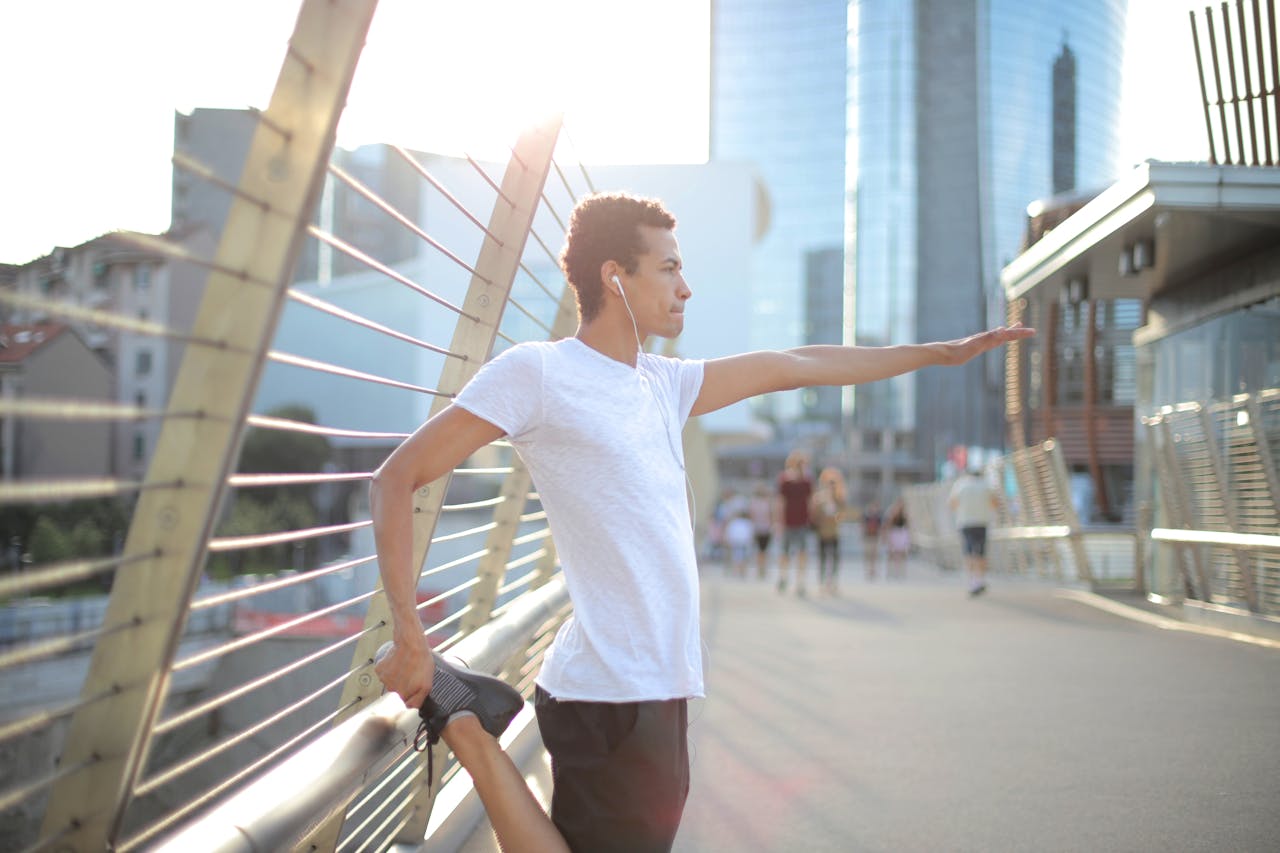 Photo by Andrea Piacquadio: https://www.pexels.com/photo/focused-millennial-ethnic-sportsman-in-earbuds-listening-to-music-and-stretching-legs-before-training-on-street-in-city-3799368/